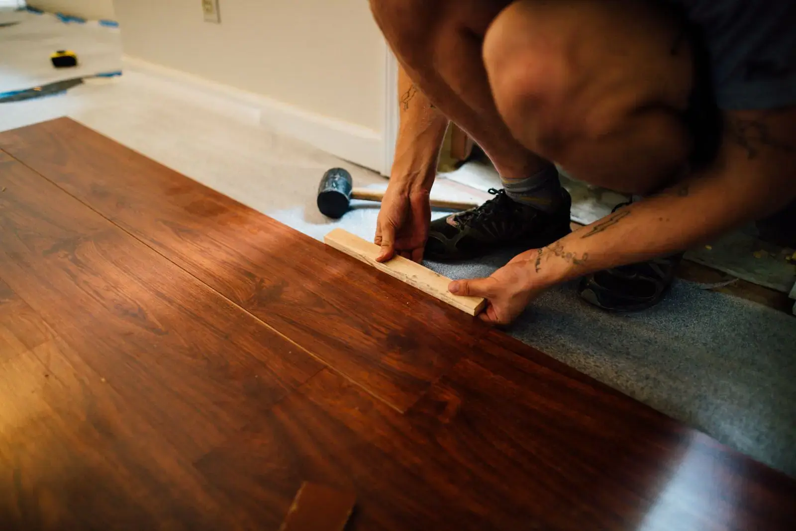 Fitter tapping a laminate board into place
