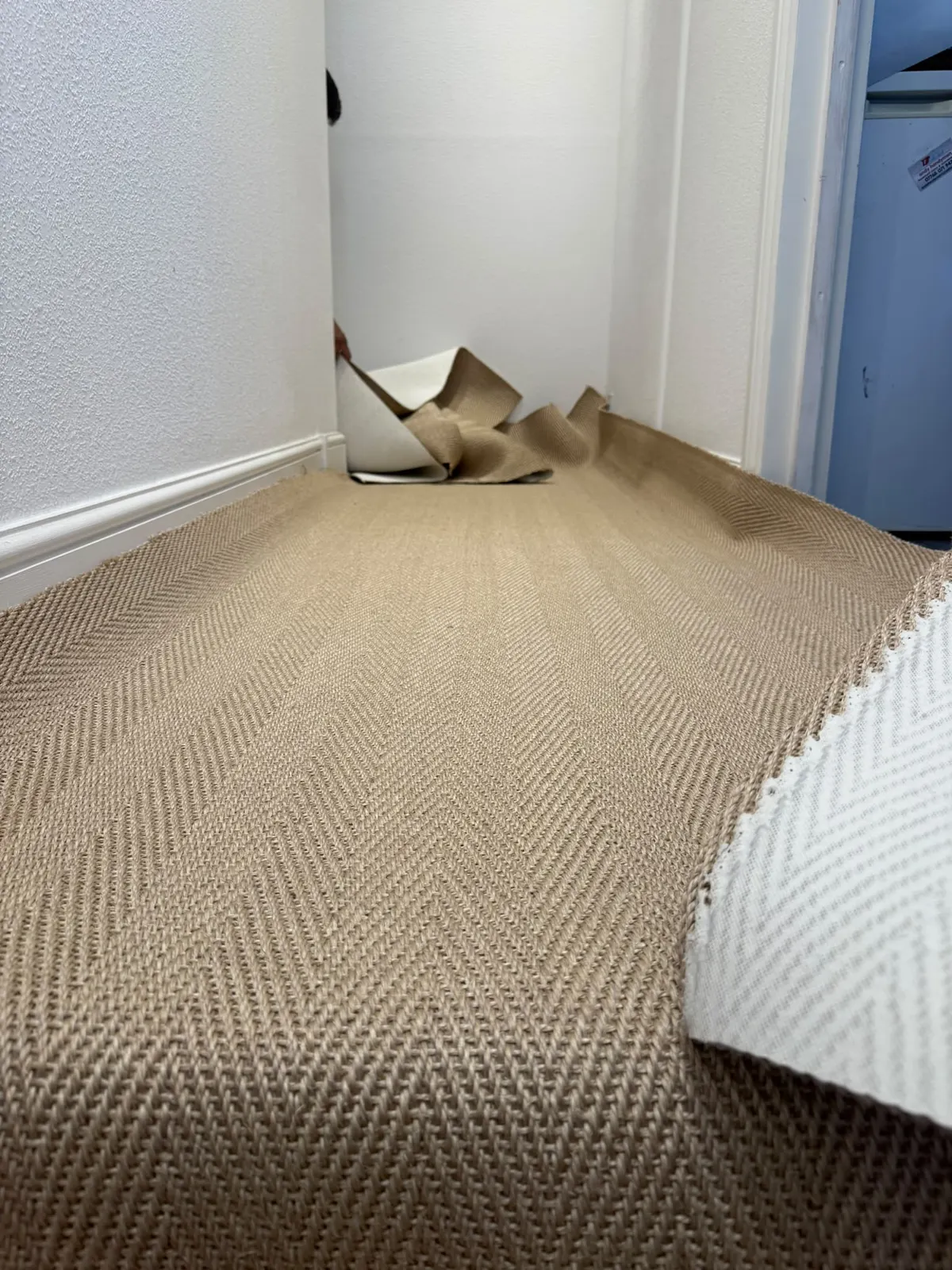 Herringbone sisal being fitted in a hallway