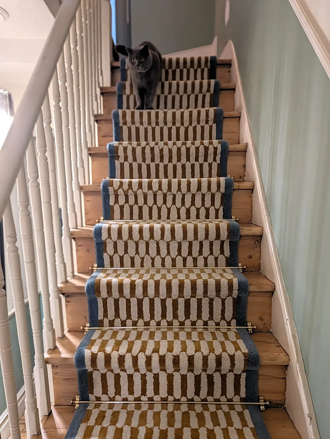 Patterned stair runner with brass rods on a pine staircase
