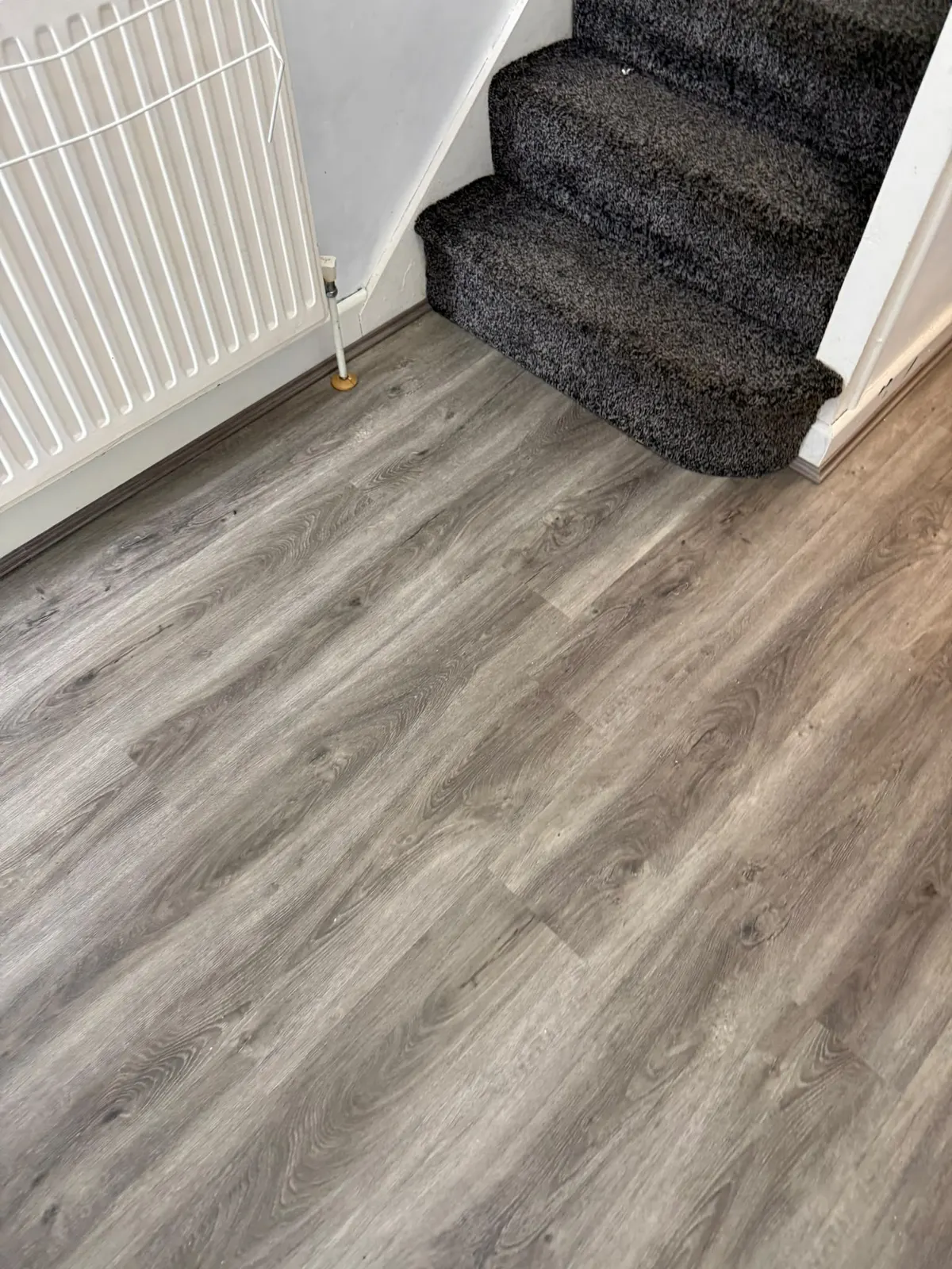 Grey wood-effect floor fitted at the foot of the stairs