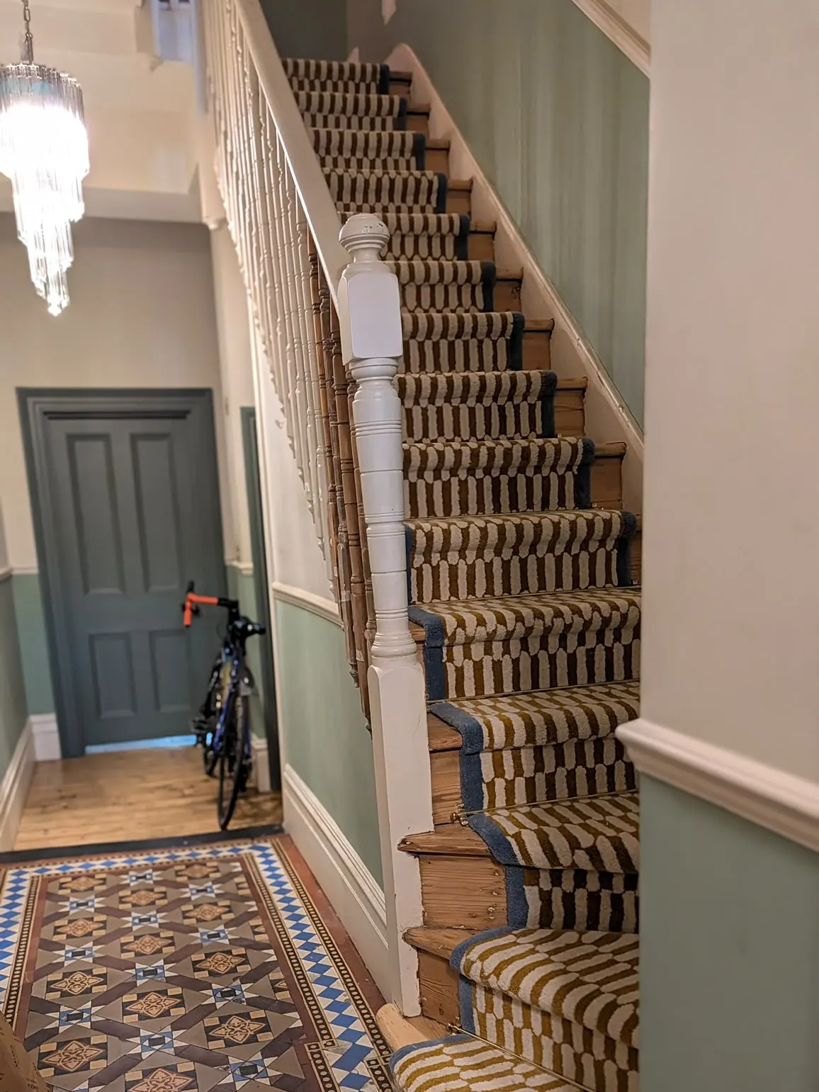 Patterned stair runner above a Victorian tiled hallway