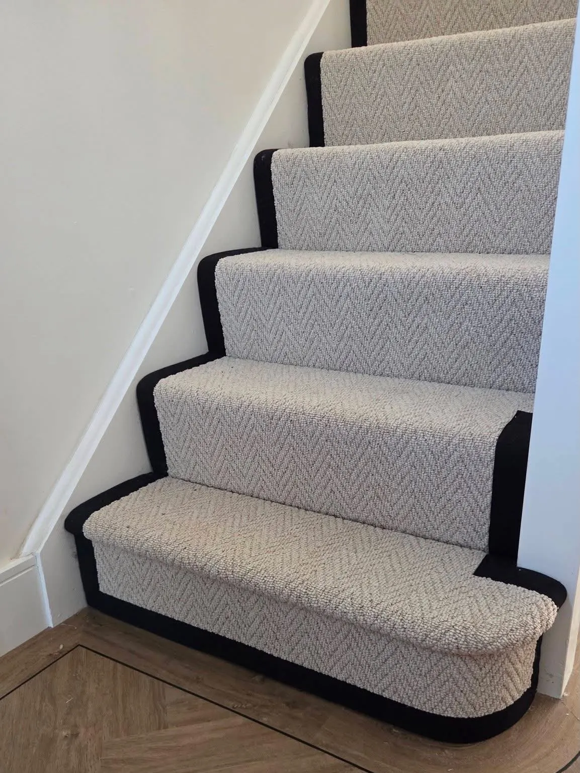 Herringbone stair runner with black border over herringbone floor