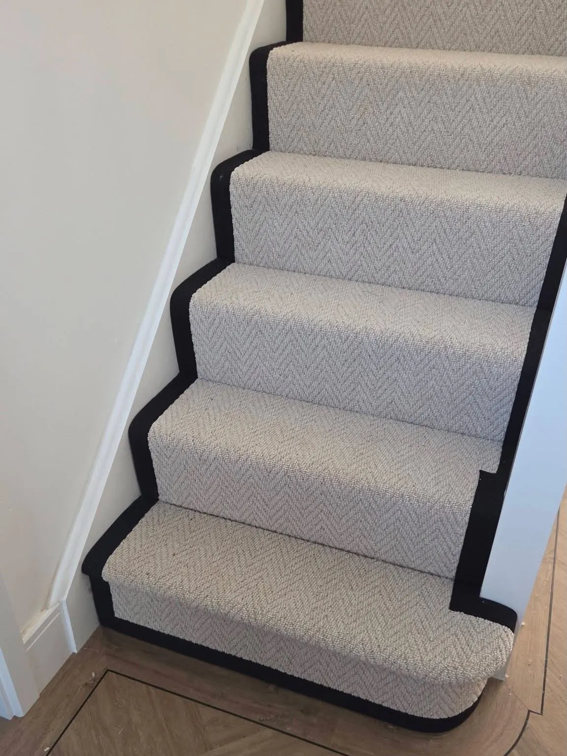 Herringbone stair runner with a curved bottom step