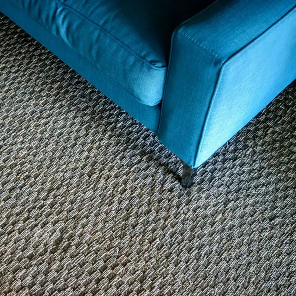 Woven carpet under a blue sofa
