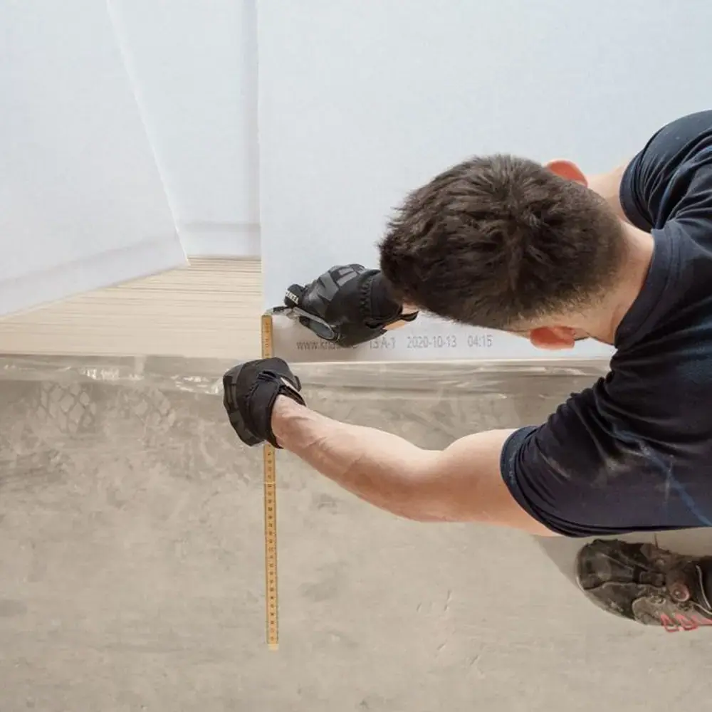 Fitter measuring a floor before laying boards